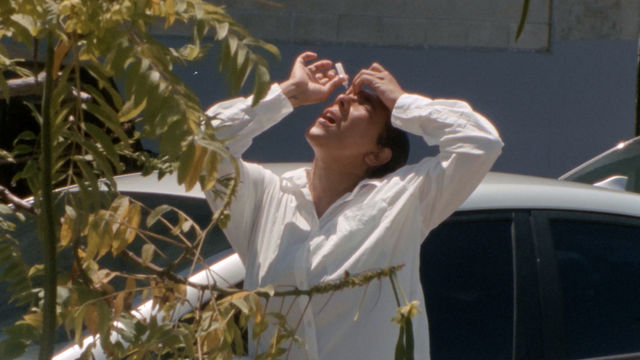 A figure in a white dress shirt and black pants puts eyedrops in her eyes