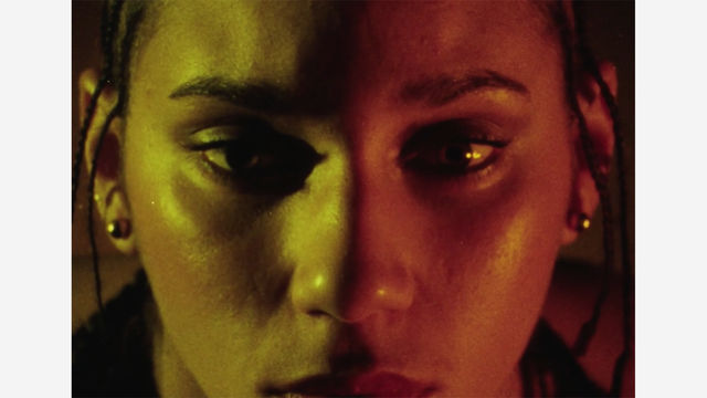 Close up of a woman's face, half bathed in yellow light