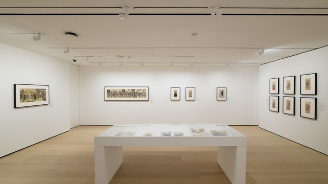 Gallery with framed works on paper installed on walls and inside a vitrine