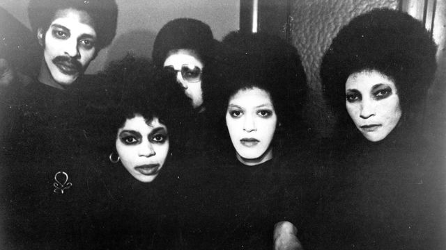 black and white still from hi mom of group with white face paint staring into camera