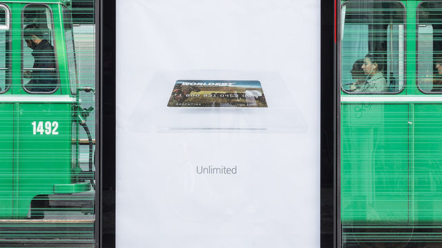 A large advertising poster at Messeplatz station shows a "Worldebt" credit card and the tagline "Unlimited"