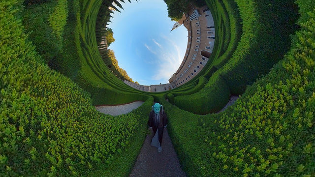 Still of a figure walking in a garden, with the image distorted into a