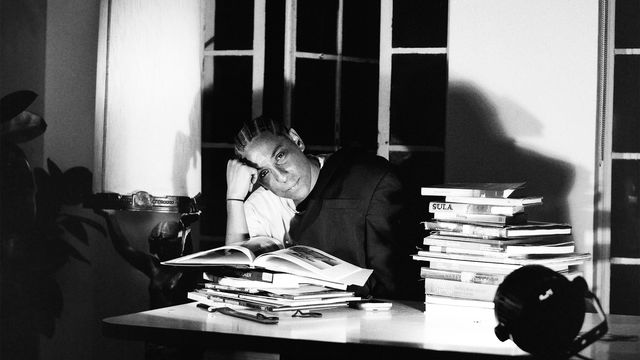 Leilah Weinraub sits at a table behind a stack of books