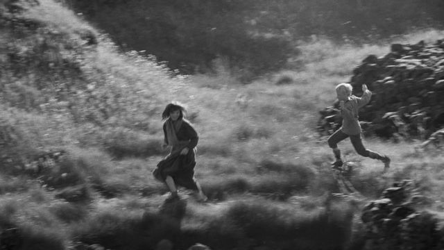 girl and boy running through field, b&w