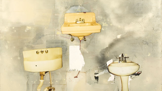 Three dingy sinks arranged in a triangle on a gray wall