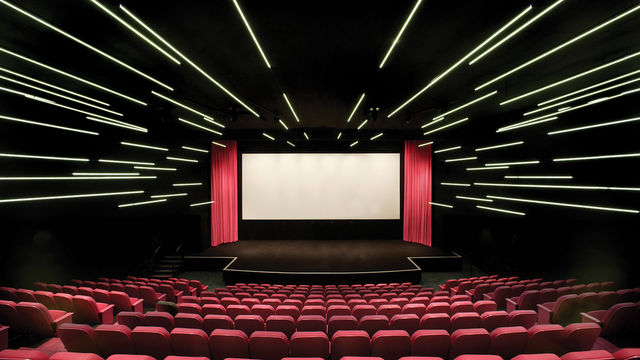 An empty movie theater with pink curtains and seats