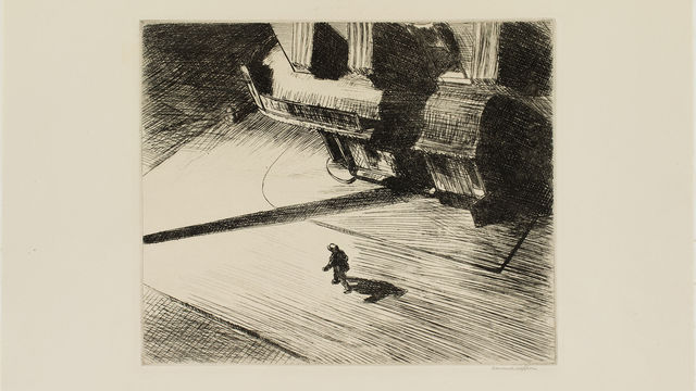 Overhead view of a city corner, with a lone figure walking down the street