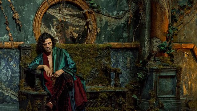 Oscar Isaac as Dr. Frankenstein, dressed in lush robes, sits pensively on a bench overgrown with weeds