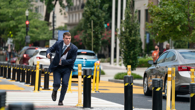 A man in a blue suit runs down a city street