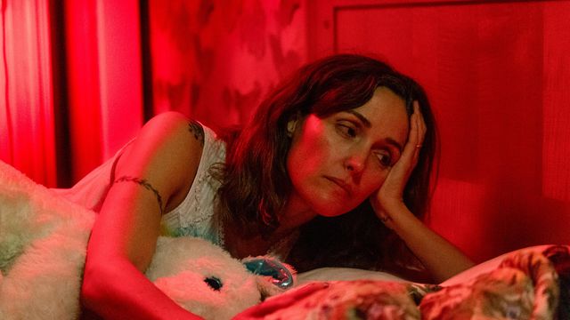 Rose Byrne lays in a bed holding a stuffed animal