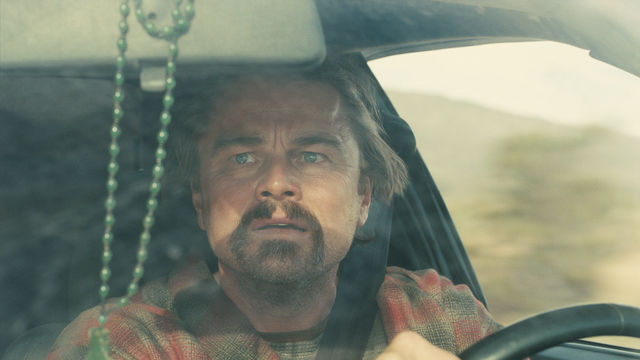 Leonardo DiCaprio drives, looking anxiously into the rear view mirror