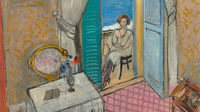 A seated woman seen through an open door, with the ocean visible beyond