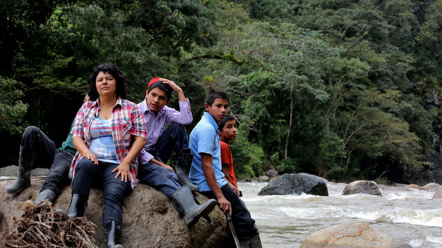 Berta Cáceres and four young men sit on a boulder in a river
