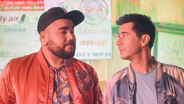 Two young men in silk jackets look at one another