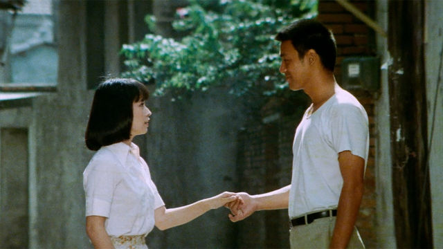 A man and woman hold hands and look into each other's eyes