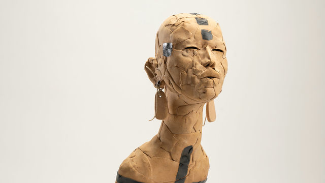 Ceramic figure with long earrings, body enveloped in beaded necklaces