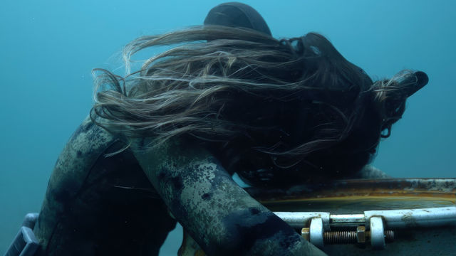 Underwater scene of a diver holding onto a sunken barrel