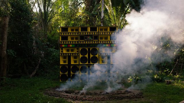 A wall of yellow speakers, surrounded by smoke