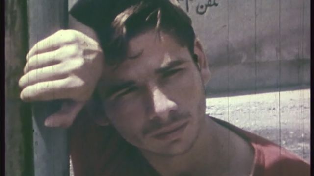 Close up of a young man leaning against a pole