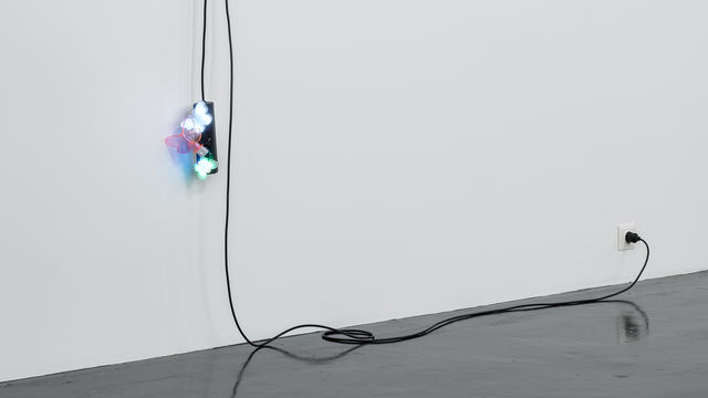 A black extension cord hangs from a wall, with three butterfly nightlights plugged into it