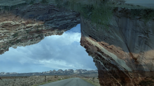 A onpen road on a barren landscape framed by canyons.