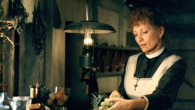 A woman in an apron handles a bunch of grapes