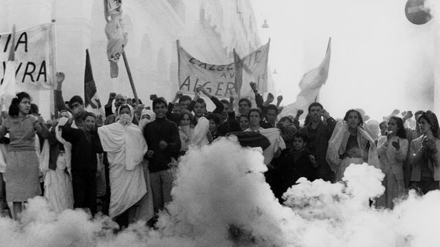 People protest in a street, surrounded by white smoke