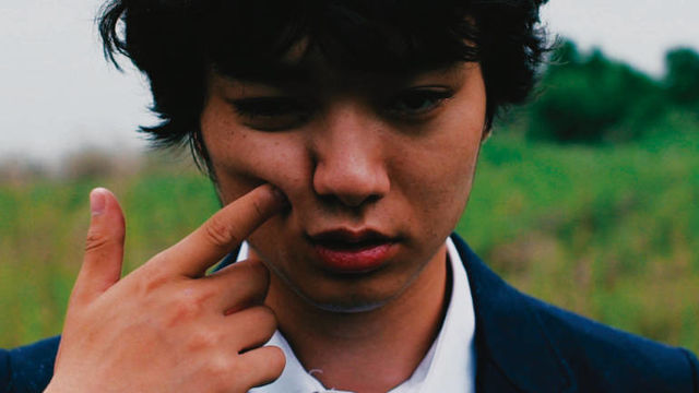 Close-up of a young man's face, with a finger pointing into their cheek