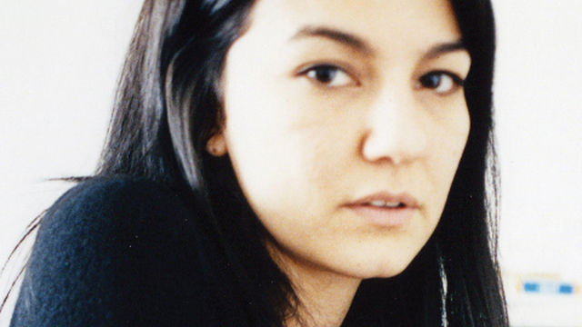 woman with long dark hair looks at camera