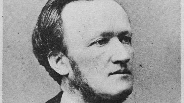 black and white portrait photograph of Wagner, shown at 3/4 angle. He wears a white shirt and loose tie, with black jacket, and has light skin, dark hair, and a cropped chin beard.