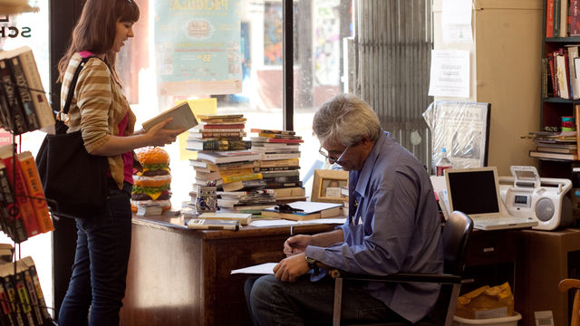 Woman reads book next to man at a desk