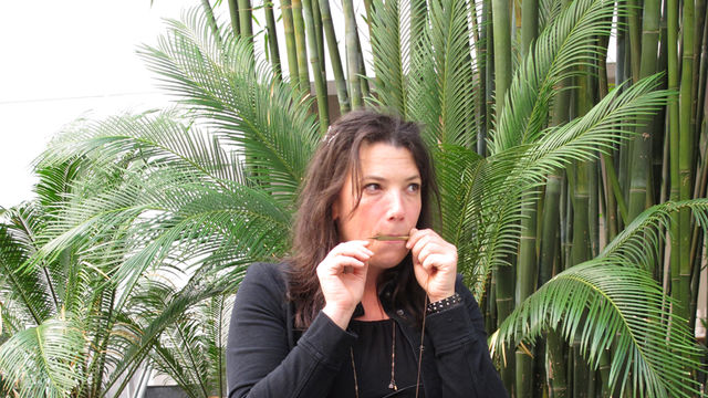 A woman kneels and plays a small mouth instrument