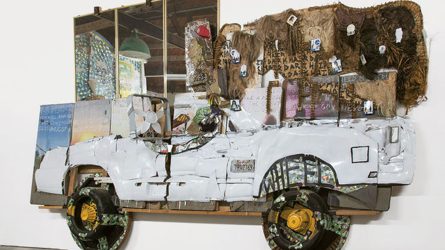 Aaron Fowler, El Camino, 2017. Acrylic paint, enamel paint, car parts, hair weave, mirrors, CDs, fans, fitted cap, tires, poker tables, speakers, digital printout, and concrete cement on conference tables. 132 x 168 x 48 in. (335.3 x 426.7 x 121.9 cm). Courtesy the artist.