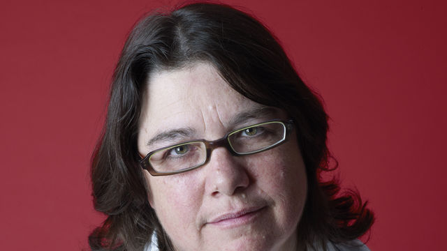 Photograph of Cathy Opie against a red backdrop.