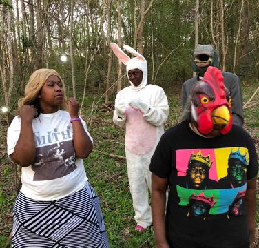 Photo of four people standing in front of a stand of trees
