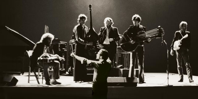 Black and white still from the film "The Last Waltz" (1978) showing a band performing with a conductor