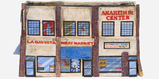Ceramic figure of a building in miniature, with signs reading "Anaheim St. Center" and "La Gaviota Meat Market"