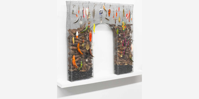 Archway made of chicken wire fill of sweet potatoes and strewn with fishing lures