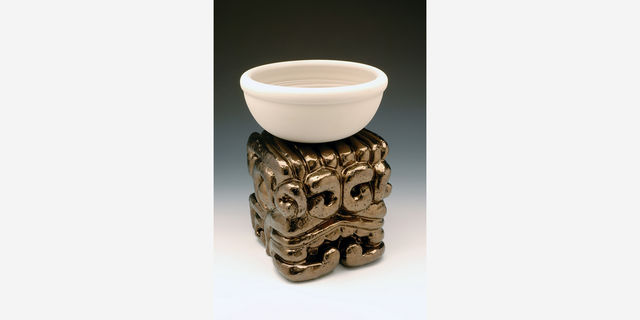 A plain bowl sits on an ornate metallic stand