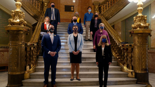 Ten people standing on an ornate staircase