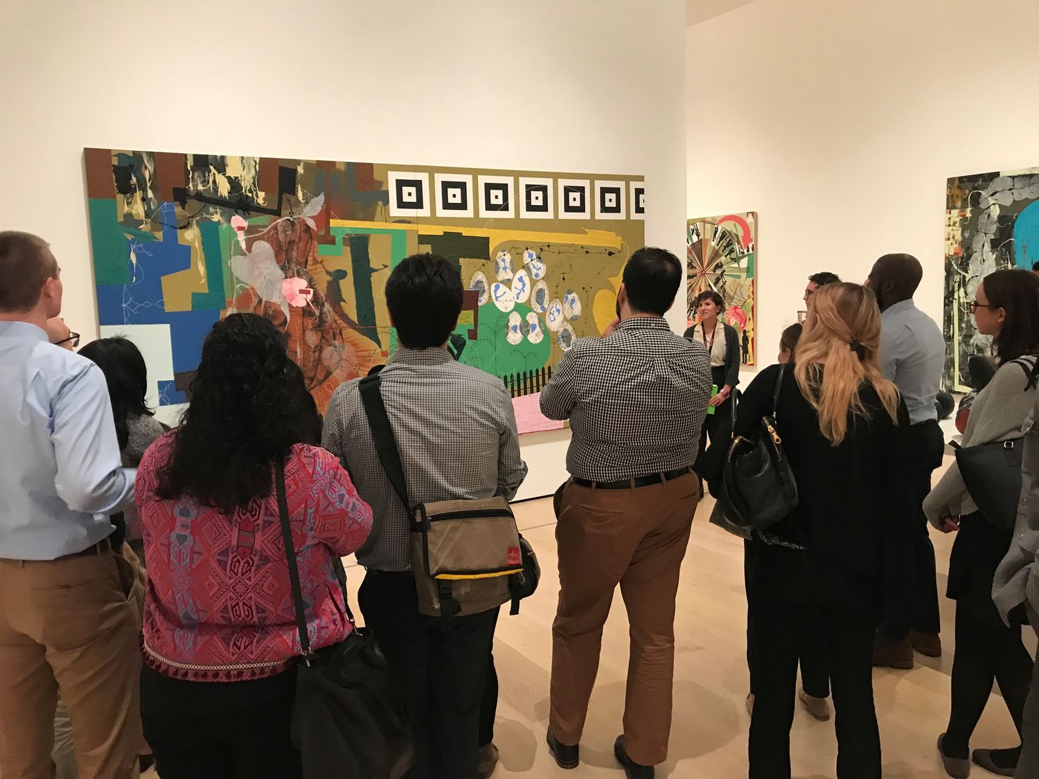 A group of people in a gallery, looking at a painting on the wall