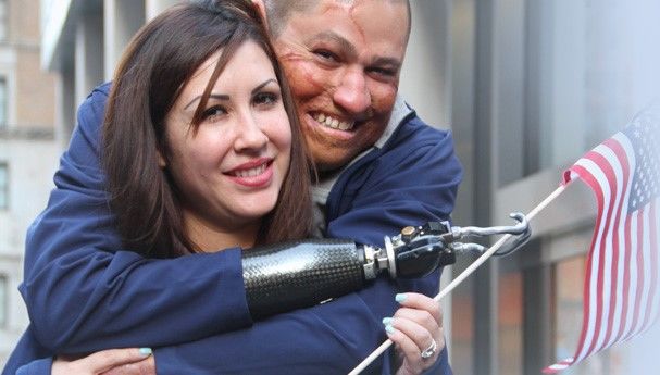 A veteran with a prosthetic hand hugs a smiling woman