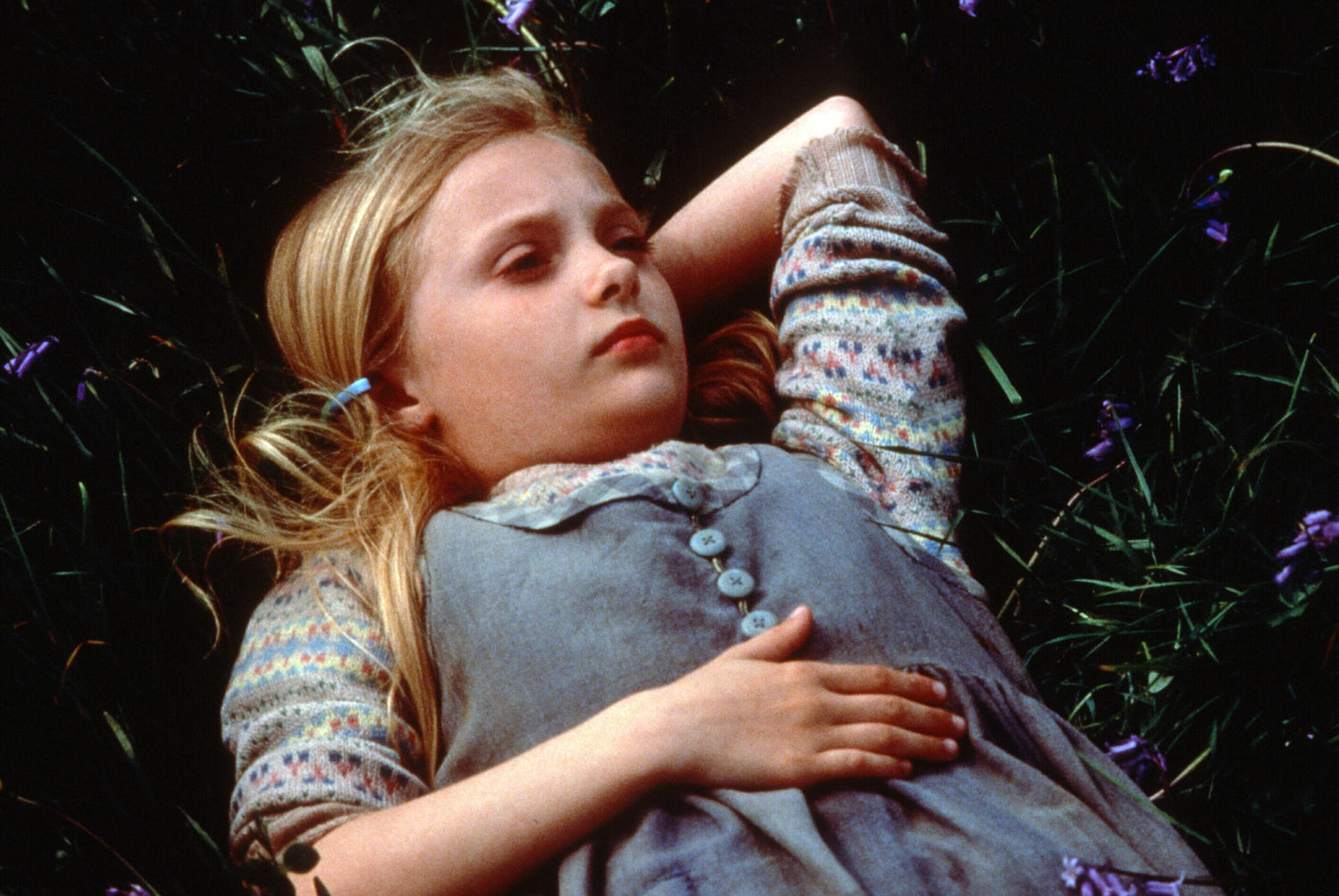 Still from the film The Secret of Roan Inish (1994) showing a young girl laying in the grass looking up at the sky