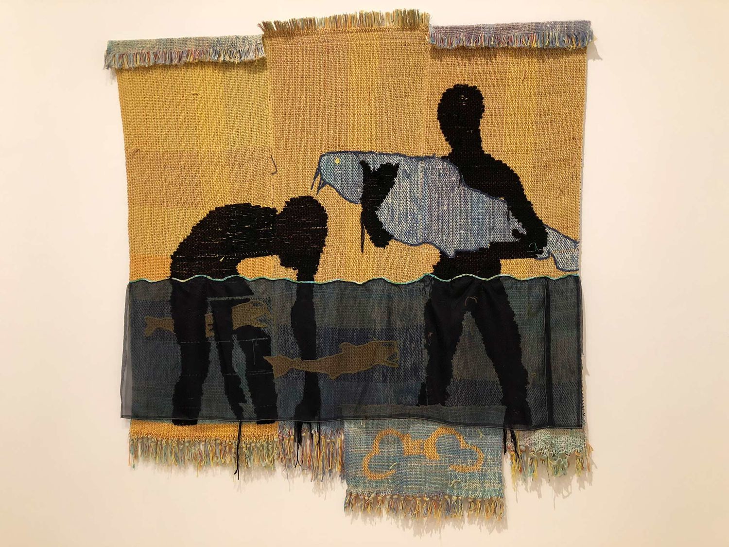 A woven tapestry of two men standing in a river holding fish