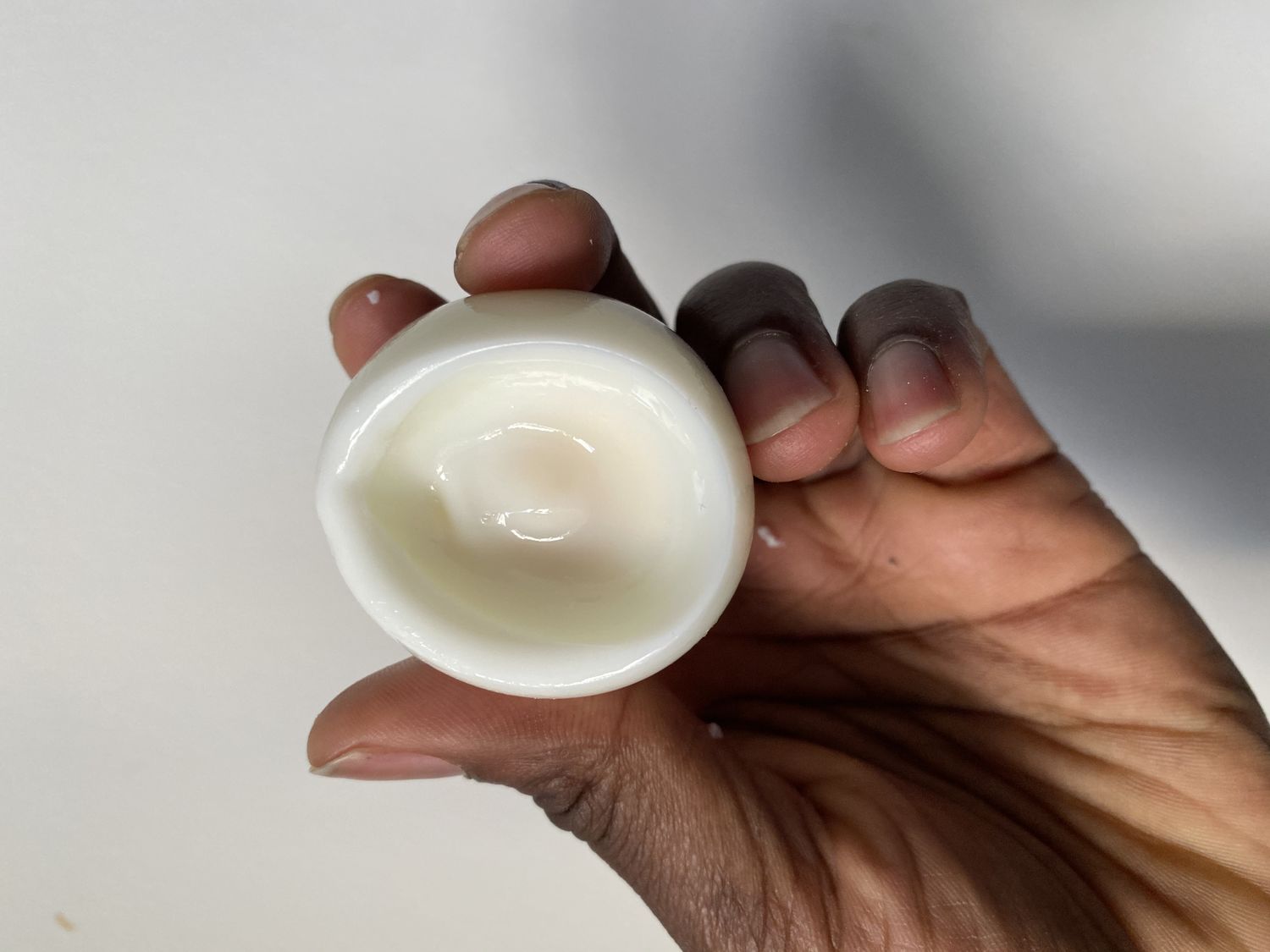 A hand holds a hardboiled egg