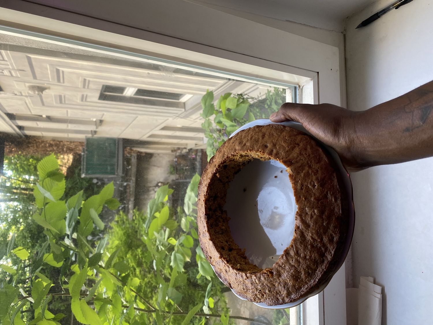 A hand holds a round cake with only the edges remaining