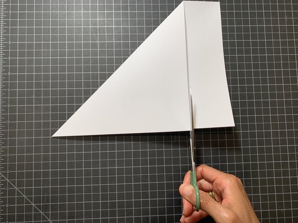 A folded piece of paper where the right hand side that is outside of the fold is being cut