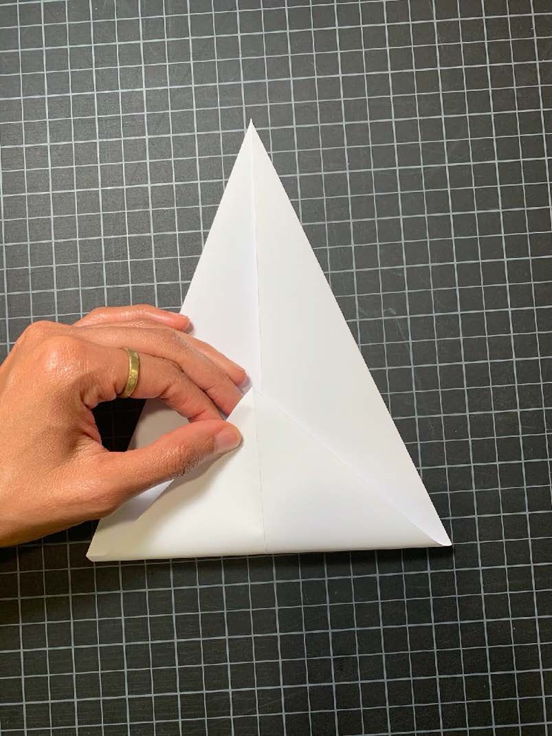 A piece of folded diamond shaped paper with the bottom point coming into the center