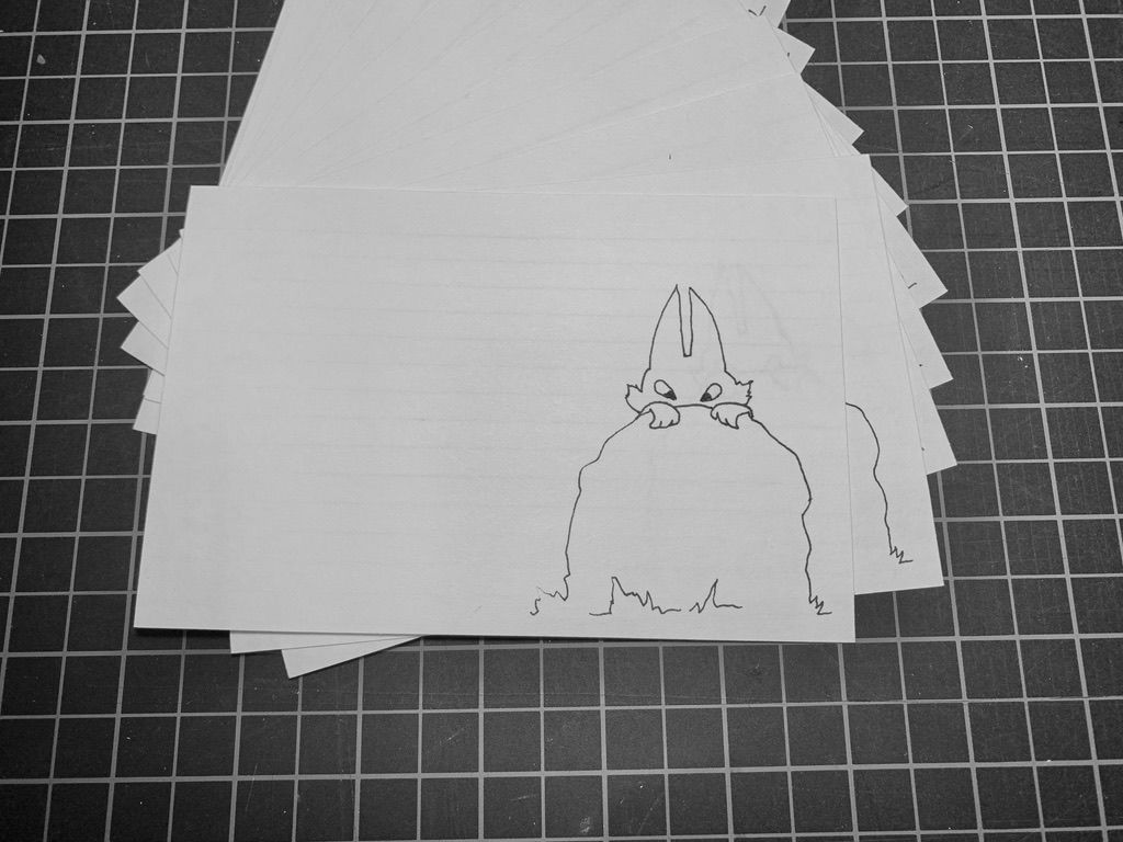 Pencil drawing of a fox peeking out from behind a rock on a white card. Black and white grid in the background.