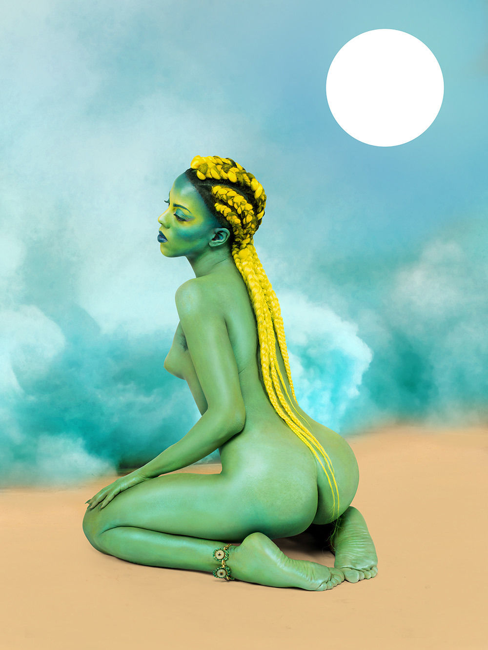 A nude woman with green skin and bright yellow braids kneels on a beach